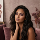 Woman with dark hair and makeup sitting on a couch with a floral background