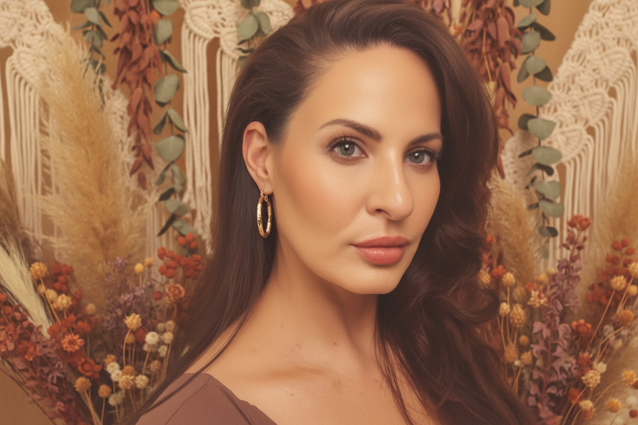 Woman with long brown hair and hoop earrings against a neutral background